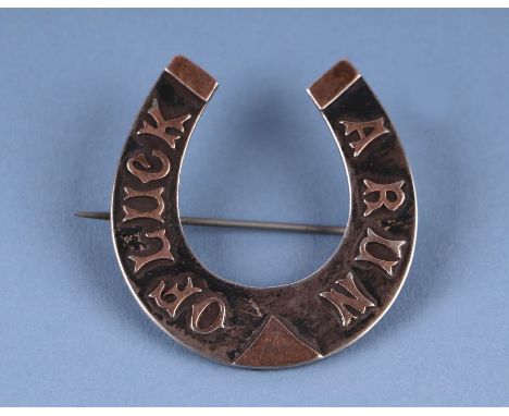 A gold mounted silver horseshoe brooch with the motto 'A Run of Luck', with 'Augustus Harriss Compts' engraved to verso (Augu