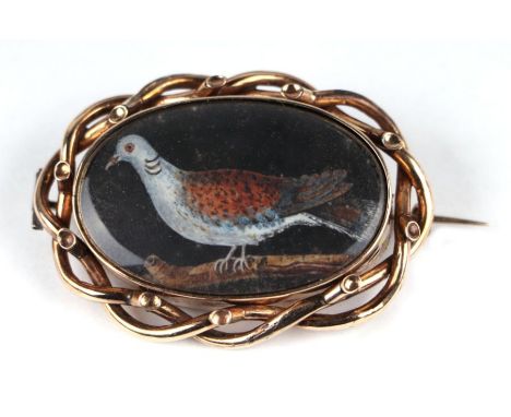 A Victorian mourning brooch inset with a portrait of a dove and the reverse with hair panel, dedication inscription for 1852,