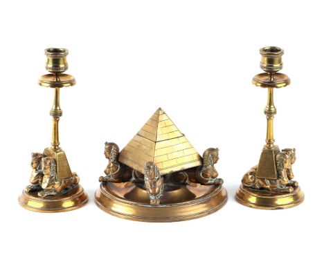 An Egyptian Revival brass pyramid and sphinx inkstand; together with a pair of matching candlesticks (3).Condition ReportOne 
