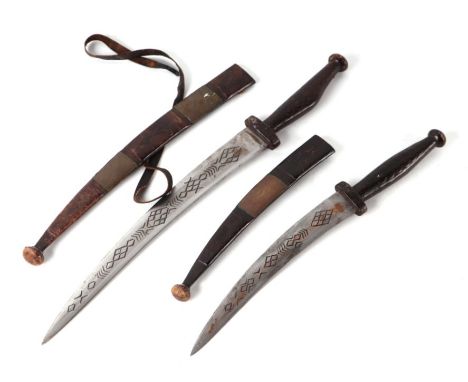 A Middle Eastern type dagger with engraved steel blade, in a leather scabbard, 44cms long; together with another similar, 35c