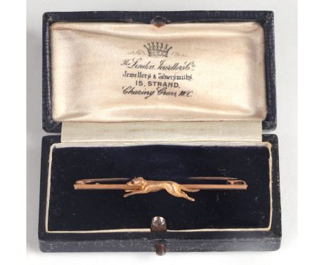 A 9ct gold stock pin n the form of a running hound with ruby eye, in a leather box.