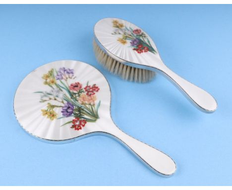 A silver and enamel hand mirror decorated with flowers; together with a matching hair brush, London 1958 (2).Condition Report