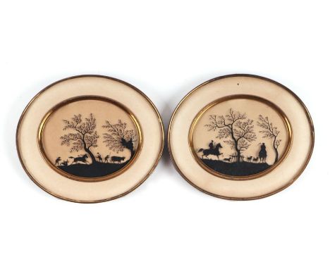 A pair of paper silhouette cut pictures depicting hunting scenes, glazed and in brass oval frames, each overall 11.5 by 10cms