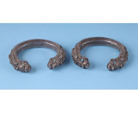 A pair of Chinese silver bullion bangles in the form of double headed dragons with turquoise eyes, each 7.5cms wide, 345g(2).