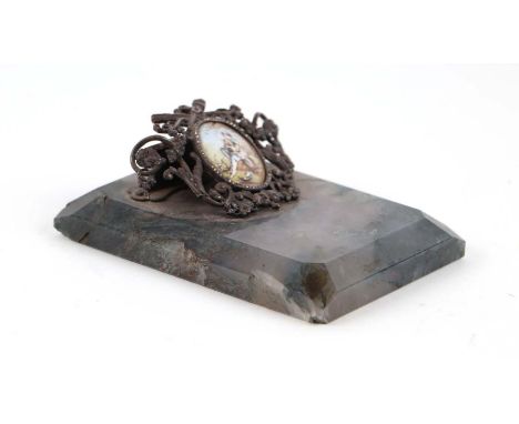 A 19th century desk top letter clip, pierced white metal with central enamel oval plaque decorated an 18th century gentleman 
