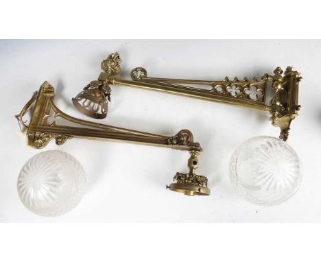 A near pair of late 20th century Gothic style gilt brass single-light wall sconces, each with a cut glass shade and pierced a