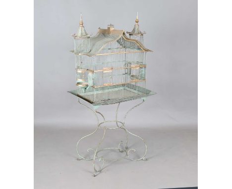 An early 20th century green painted wirework architectural birdcage, raised on a rectangular tray and scrollwork stand, heigh