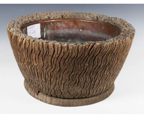 A 19th century Japanese carved wooden circular hibachi, naturalistically carved as a wooden trunk and fitted with a brass lin