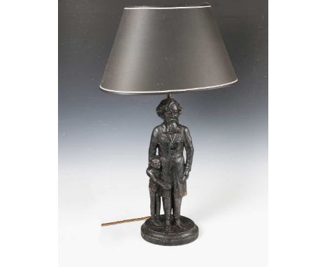 A Victorian cast iron figure group of Charles Dickens and Oliver, later converted to a table lamp with black shade and brass 