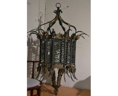 An imposing green painted iron lantern form light fitting, the twelve sided pierced scrollwork body with flared arms above an