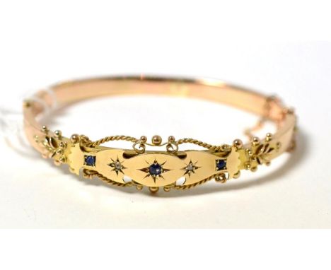 A 9ct gold sapphire and diamond bangle, the front star set with three graduated round cut sapphires and two rose cut diamonds