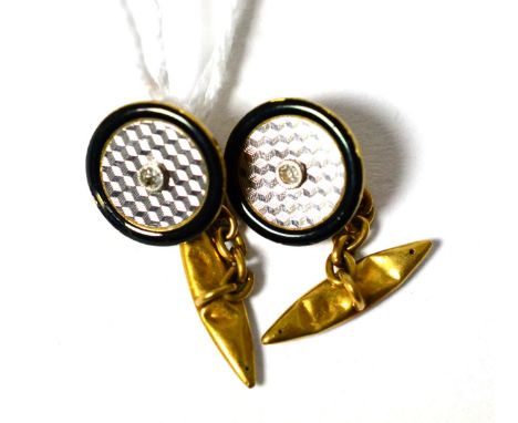 A pair of diamond cufflinks, an eight-cut diamond in a white millegrain setting within an engine turned border with a black e