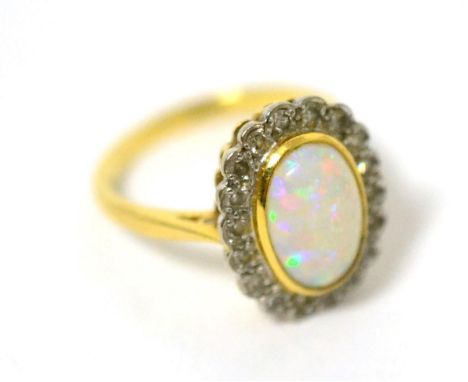 An opal and diamond cluster ring, an oval cabochon opal in a yellow bezel setting within a border of eight-cut diamonds in wh