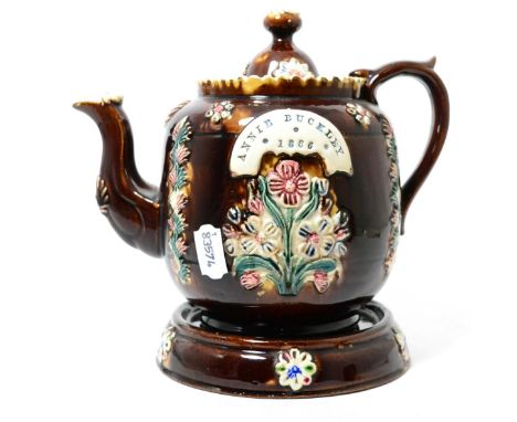 A Measham bargeware teapot, cover and stand, inscribed ANNIE BUCKELEY 1886, 24cm high      