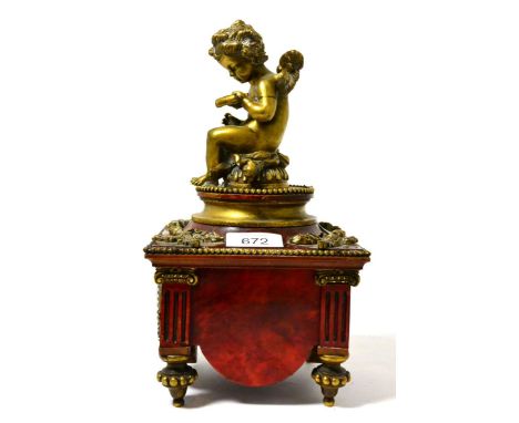 A gilt metal mounted faux red marbled wood mantel timepiece, early 20th century, of architectural form surmounted by a putto,
