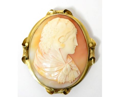 A cameo brooch, the oval carved shell cameo depicting a portrait of young Hercules in a lion skin, within a scroll edge frame