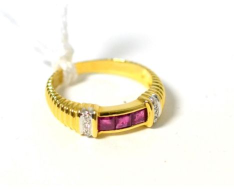 A ruby and diamond ring, three square cut rubies in yellow channel settings to diamond set shoulders, on a ribbed shank, fing