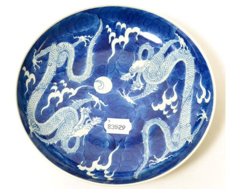 A Chinese porcelain saucer dish, painted in underglaze blue with dragons chasing the flaming pearl, bears Kangxi reign mark, 