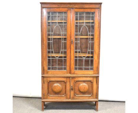 1920's oak bookcase, blind fetwork frieze, leaded glazed doors above a cupboard, width 99cm, depth 32cm, height 182cm.