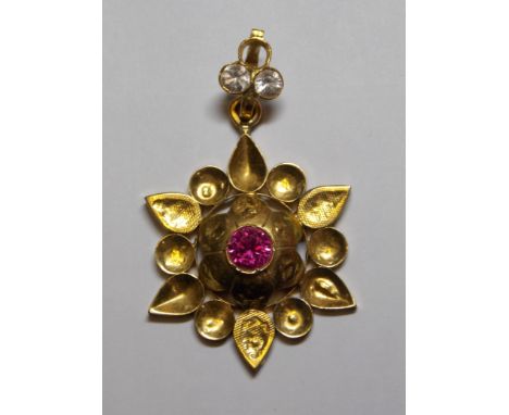 A FLOWER HEAD PENDANT INSET WITH SEED PEARLS AND RUBY COLOURED STONES - 7.7G APPROX. 