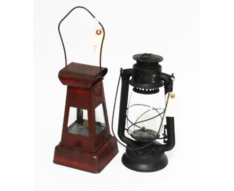A red painted metal lamp and a black storm lamp.  
