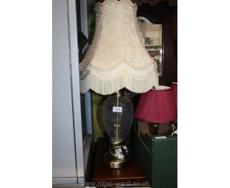 A modern Lamp having glass and metal base and cream shade.