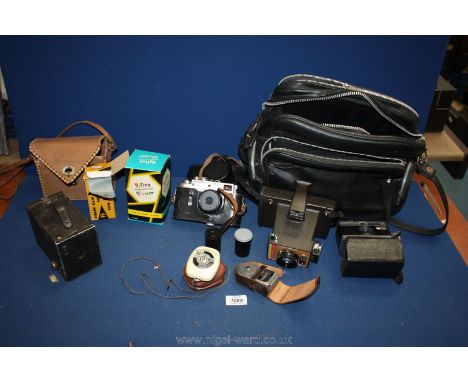 Three Cameras in a camera bag, including a Polaroid Land camera, a Zorki 4K USSR camera, two light meters, and an Instamatic 