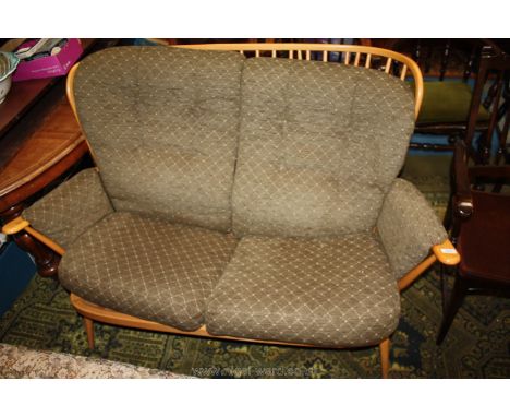 An Ercol light wood framed 2 seater stick back settee with lattice pattern green upholstery. 