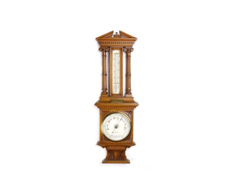 LATE VICTORIAN CARVED OAK BAROMETERwith broken arched pediment supported by two ionic colums, with thermometer and barometer 