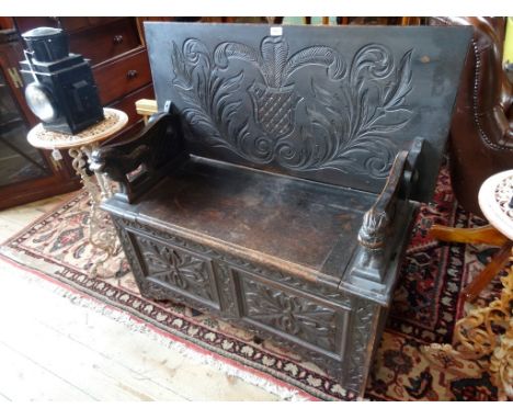 An early 20th century carved oak monks bench, (101cm wide).
