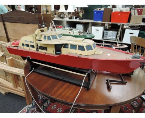 A wooden model hand built motor boat, on display  stand with remote control system