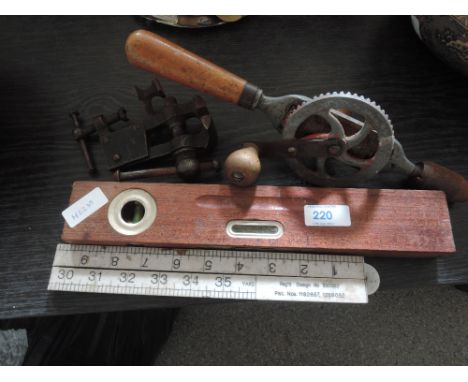 A selection of vintage hand tools including spirit level, meter rule, engineers vice and hand drill