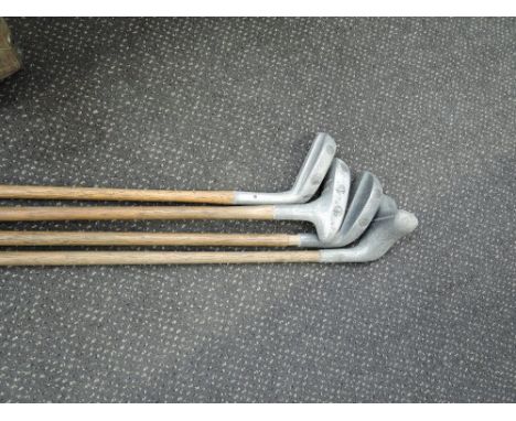 Four vintage hickory shafted golf clubs including a straight line putter in a canvas golf bag
