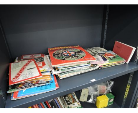 A shelf of football ephemera including 1970's and later match day programmes and tickets, 3D cards, George Best and Dennis La