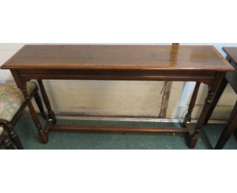 An early 20th century single stretcher oak console table cross banded in walnut with two twin baluster legs, 134cm x 33cm x 7