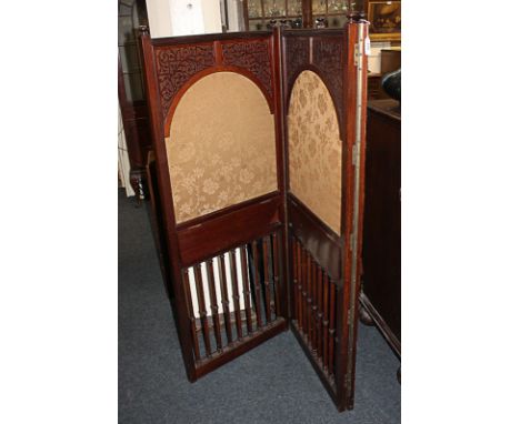 An early 20th century mahogany three-section room screen, three arched fabric panels with blind fret decoration, above open s