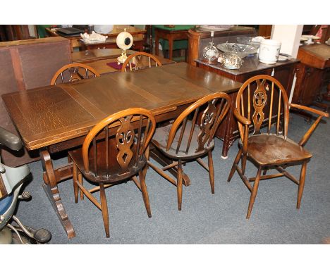 An Ercol type stained oak dining suite, comprising a rectangular dining table on trestle supports, five Windsor style dining 