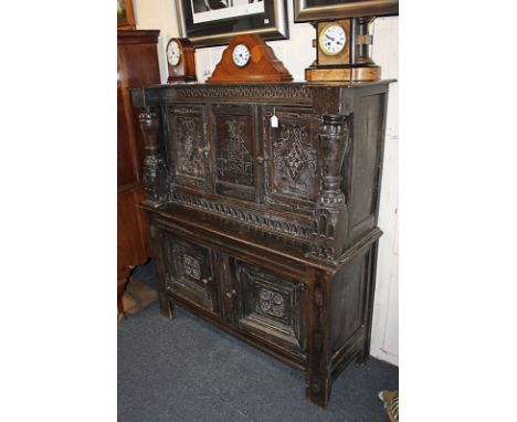 A 17th century and later carved oak cupboard, the top section with two cupboards, central panel and baluster supports, on bas