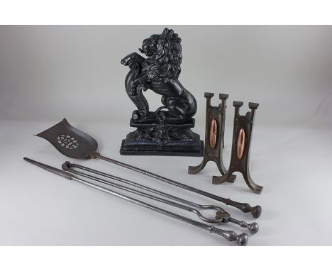 A Victorian black painted cast iron doorstop of a lion rampant, together with a pair of Arts and Crafts style fire dogs and a