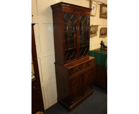 A reproduction mahogany bookcase, with two glazed panel doors enclosing two shelves, the base section with drawer and decorat