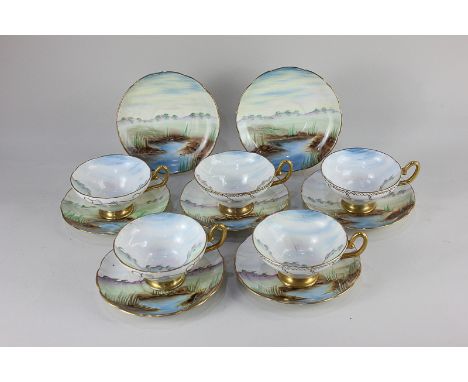An English Crystal Bone China part teaset, each piece hand painted with a scene of a lake side with hills and trees in backgr