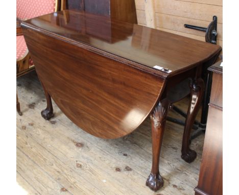 An early 19th Century oval gate leg dining table with carved claw and ball feet