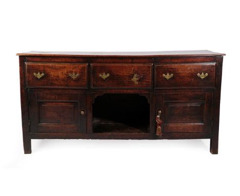 A Mid 18th Century Oak Enclosed Low Dresser, with three deep drawers above an open shelf flanked by two moulded cupboard door