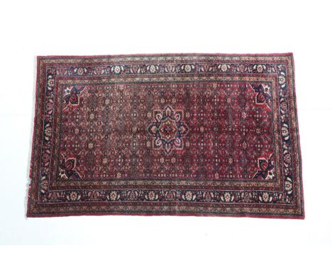 Hamadan Carpet Iranian Kurdistan, 20th century The blood red Herati field centred by a flowerhead medallion framed by spandre