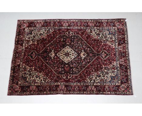 Bakhtiari Carpet West Iran, circa 1960 The deep brick red field centred by a stepped floral medallion famed by ivory spandrel