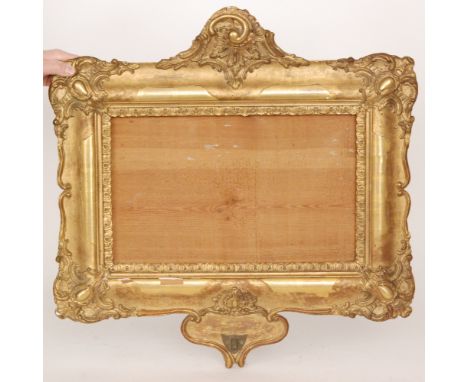 A 19th Century gilt picture frame with 'C' scroll pediment above a sconce bracket, width 63cm