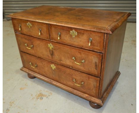 An 18th Century crossbanded walnut chest of two short and two long drawers, brass pear shaped drop handles on later bun feet,
