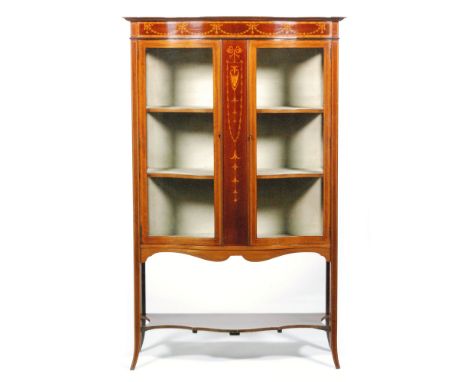 An early 20th Century Sheraton Revival serpentine-fronted mahogany salon side cabinet, with inlaid swag frieze and central pa