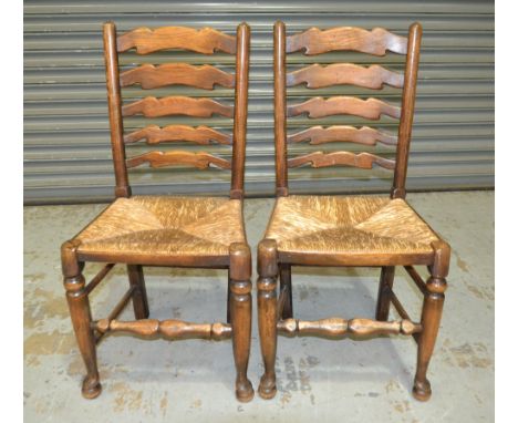 A set of six 20th Century Northern Counties oak ladder back dining chairs with rush seats, on turned legs and stretchers and 