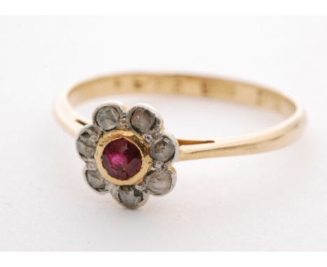 An early 20th Century ruby and diamond daisy cluster ring, central ruby within a seven stone diamond surround, all to knife e